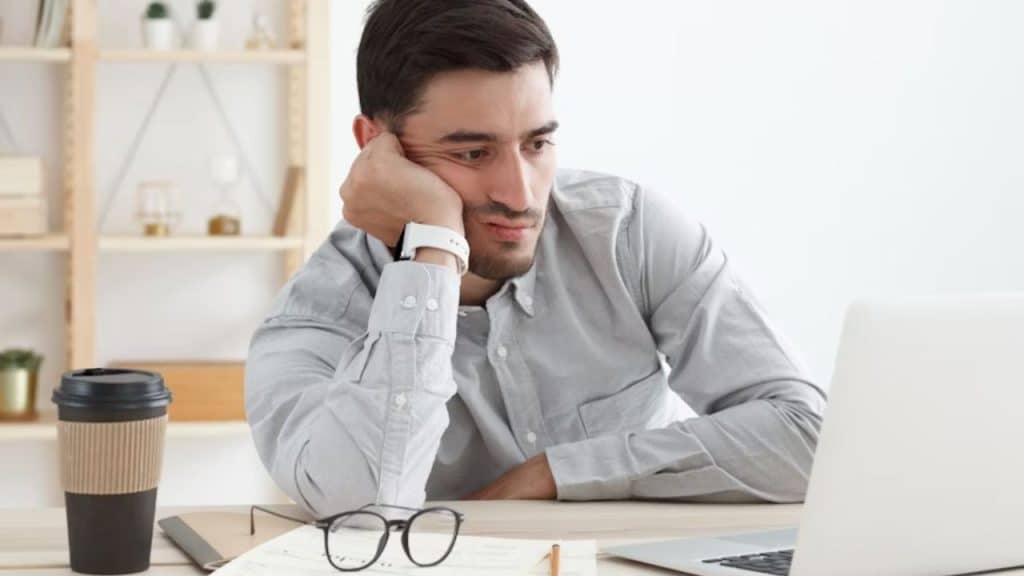 Man stressed while looking at his laptop and financial spreadsheets