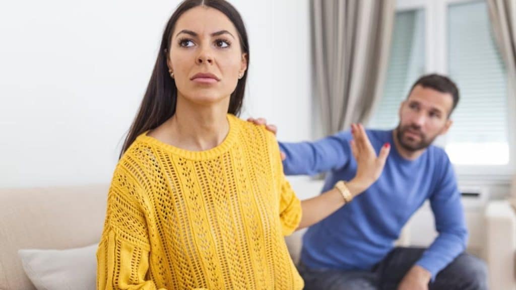 Woman frowning and raising her hand while man leans in suggestively