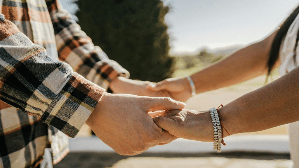 A couple holding hands outdoors.