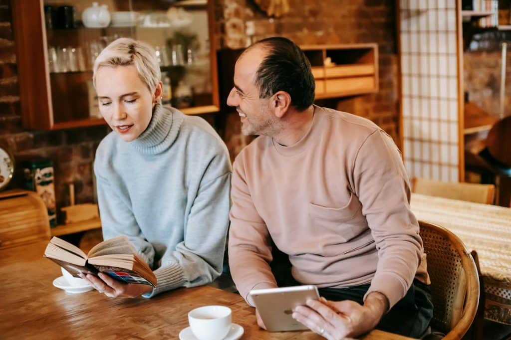 A man supporting woman reading a book