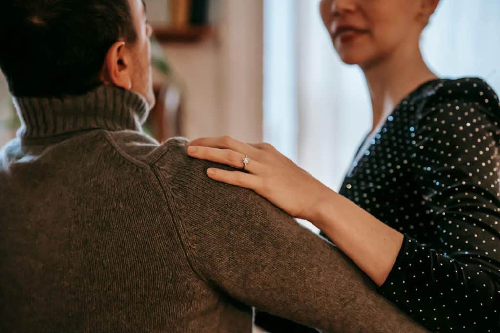 A woman resting her hand on a man’s shoulder 