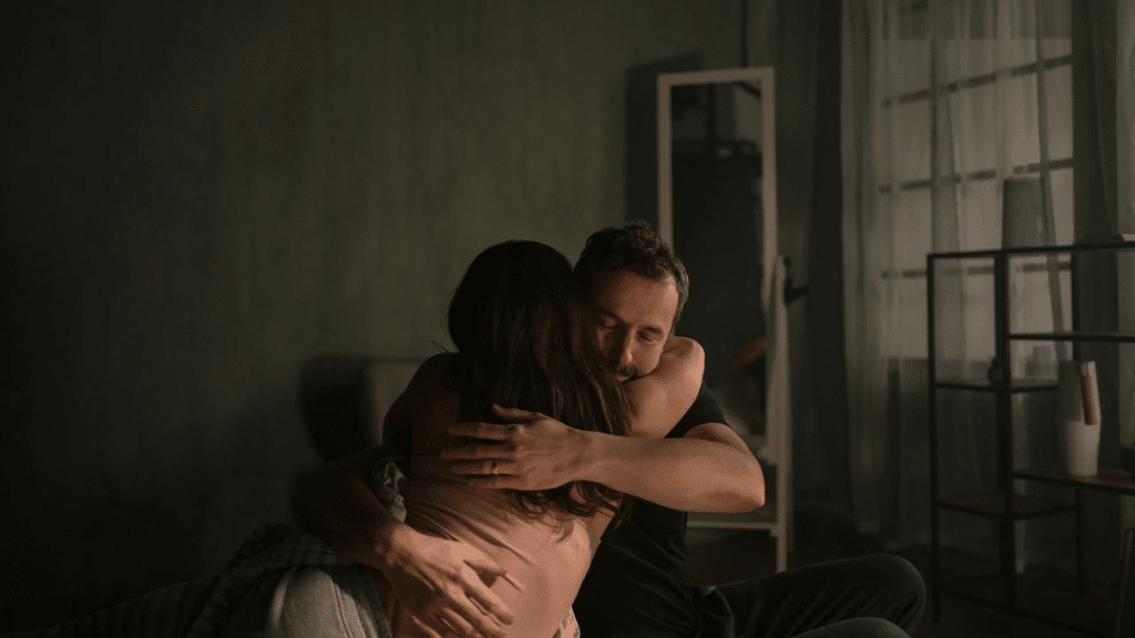 A couple hugging each other in a dimly lit room.