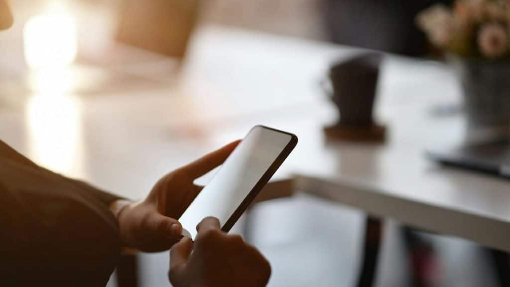 A person using a smartphone at a table indoors.