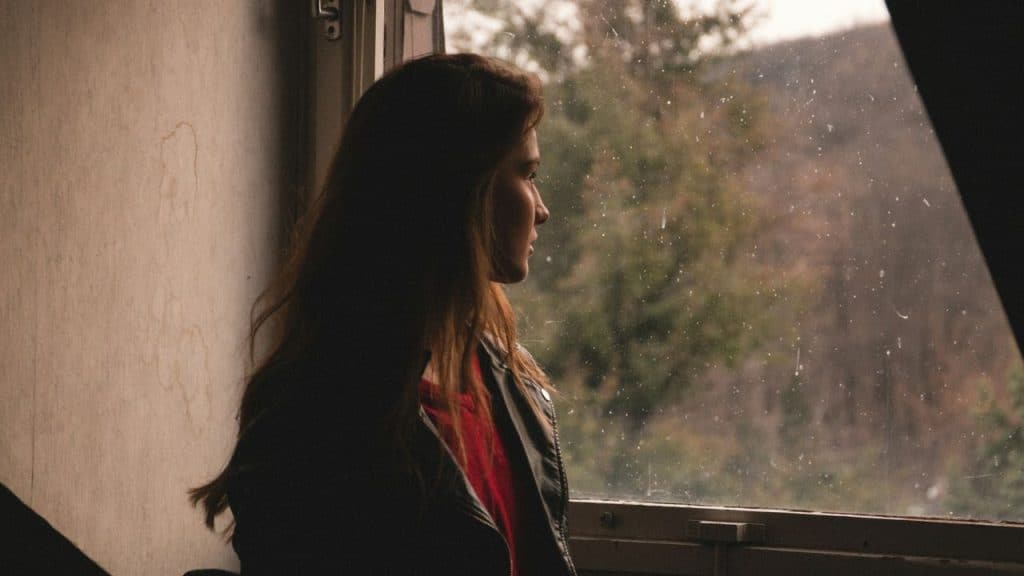 A pensive woman looks out a window on a rainy or snowy day.