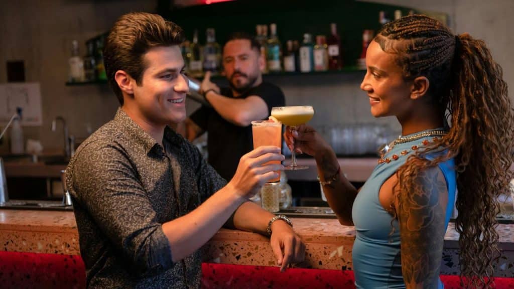 A man and a woman smile and toast with cocktails at a bar.