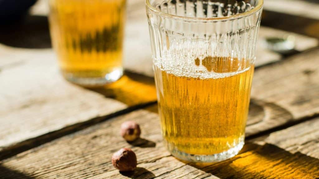 A glass of beer on a wooden table.