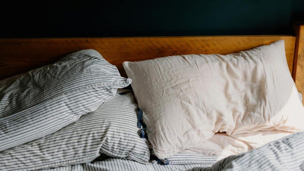A bed with striped sheets and pillows.
