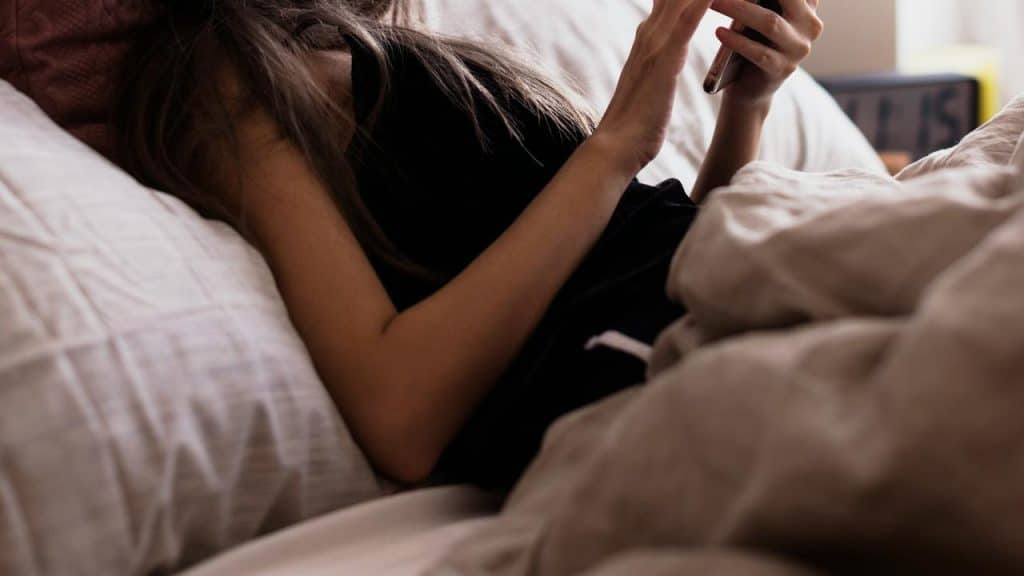 A woman lying in bed using her phone.
