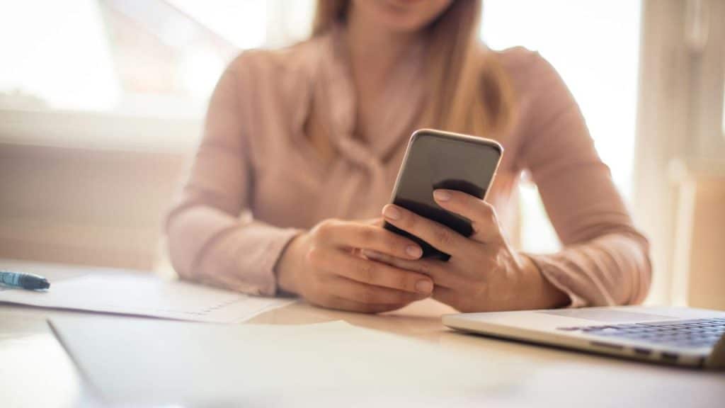 A woman using her phone at a desk.