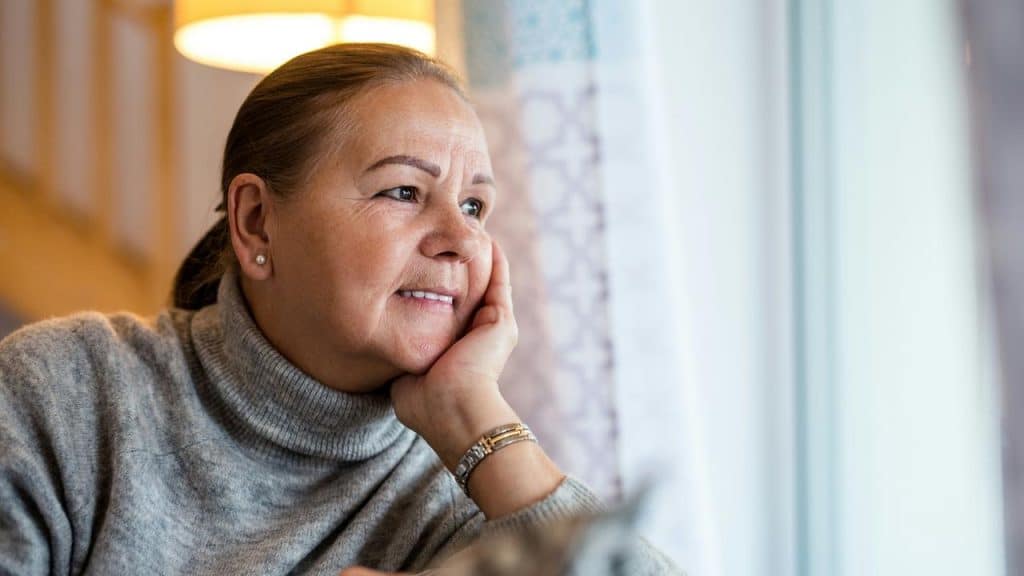A woman smiles while looking out a window.