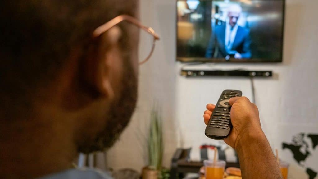 A person watching TV with a remote in hand.