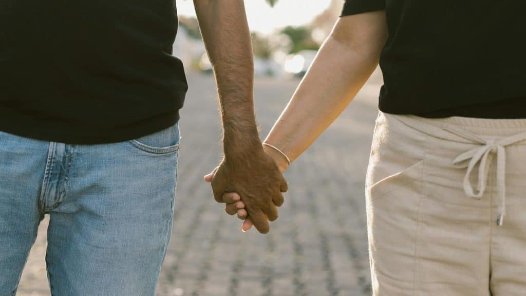 A couple holds hands while walking outdoors.