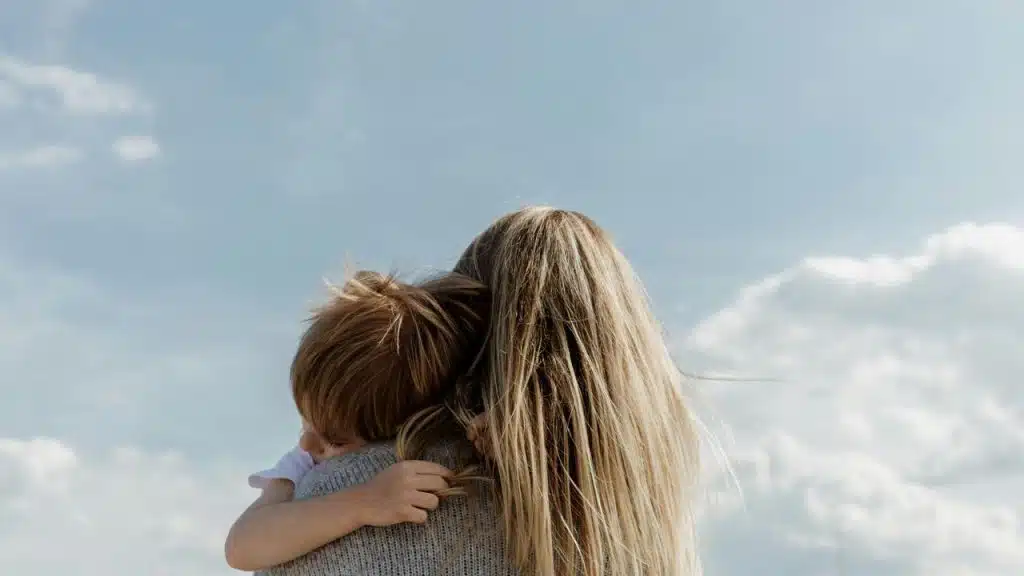 A woman holds a child while facing the sky.