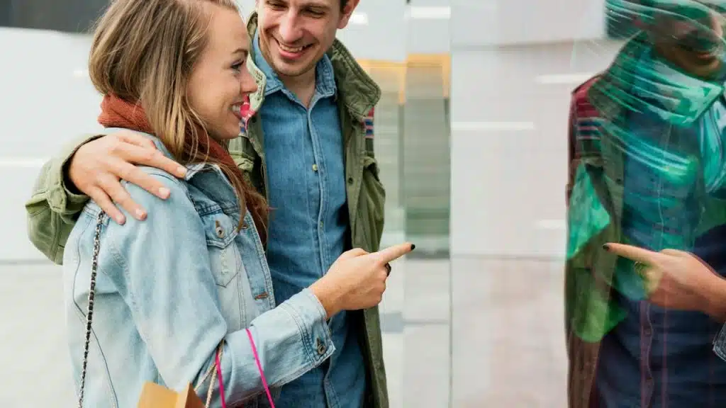 A smiling couple looks at a store window display.