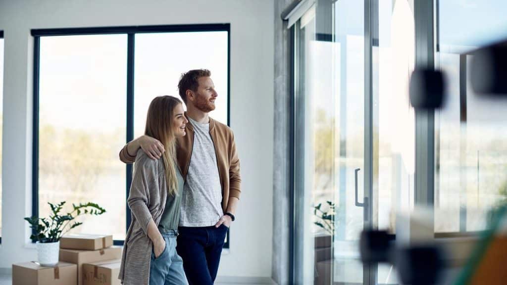A couple standing together and smiling in a bright new home.