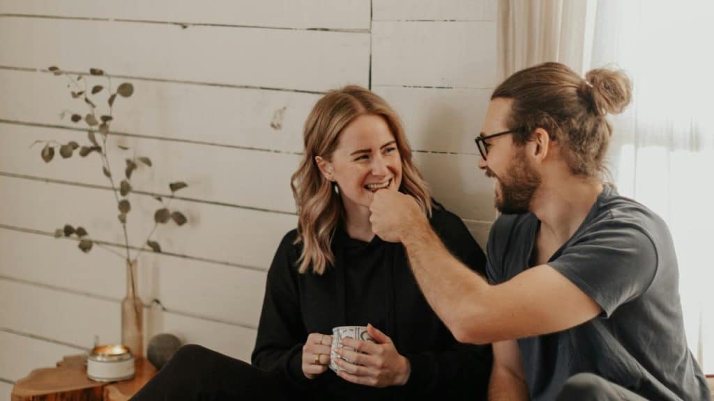 A couple laughing together while sitting indoors.