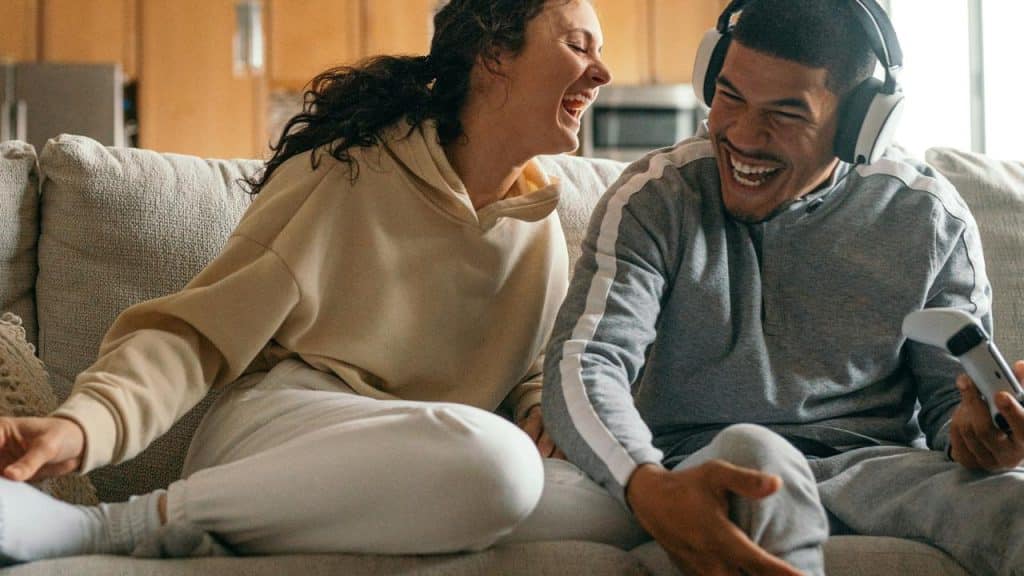A couple laughing together while sitting on a couch.