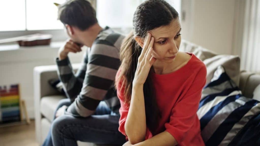 Man sitting with guilt while his partner looks upset