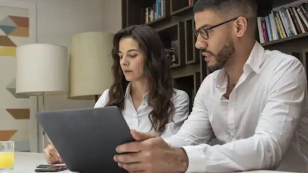 A couple feeling frustrated while discussing plans at a desk.
