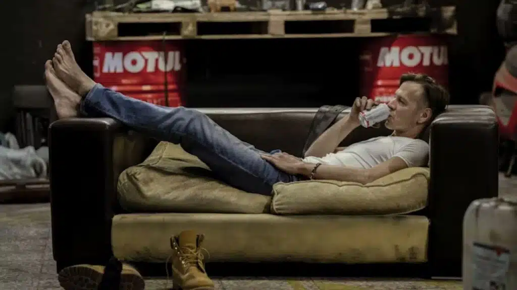 Man looking tired while slouching on the couch and drinking a can of beer