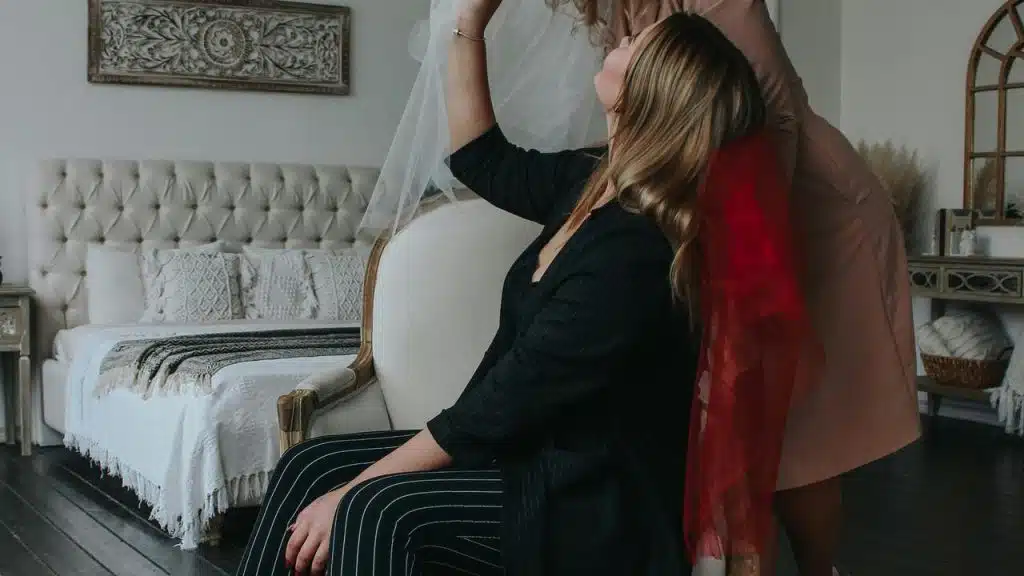 A woman sitting on a chair while another woman stands beside her.