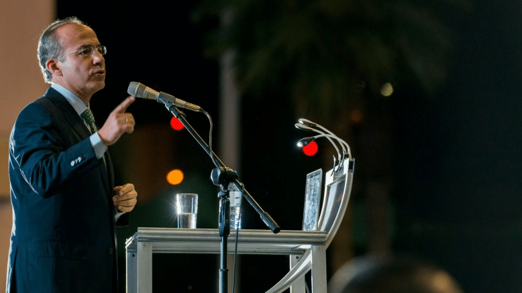 A man in a suit and tie speaks at a podium with microphones.