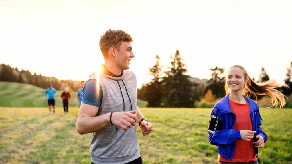 A couple running and smiling together outdoors.