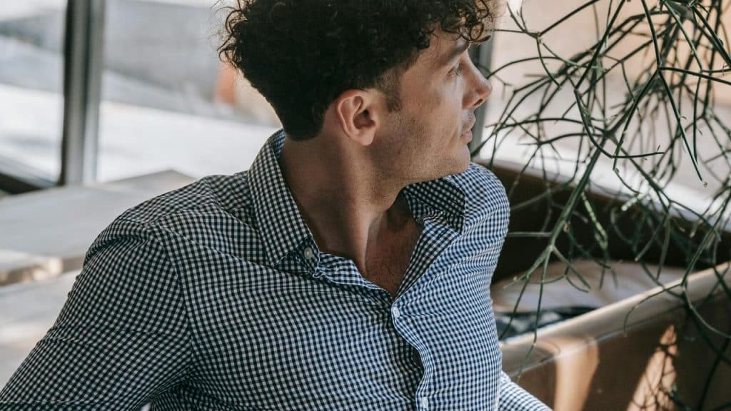 A man looks at a distance while sitting on a couch.