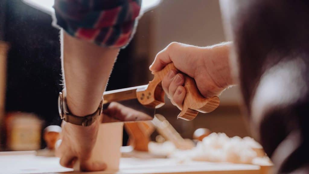 A person using a hand saw to cut wood.