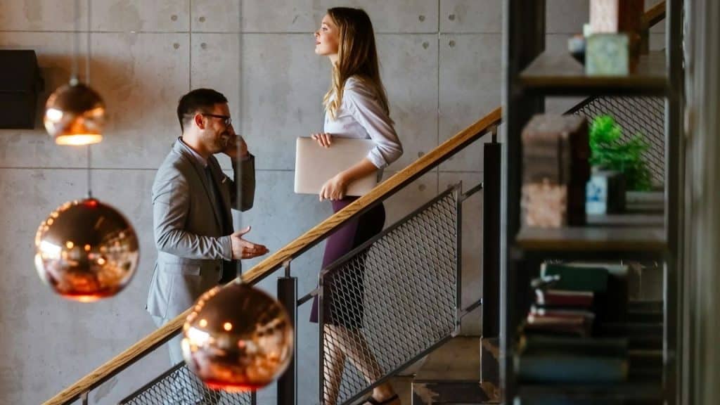 A man talks on his phone as he passes a woman on the stairs.