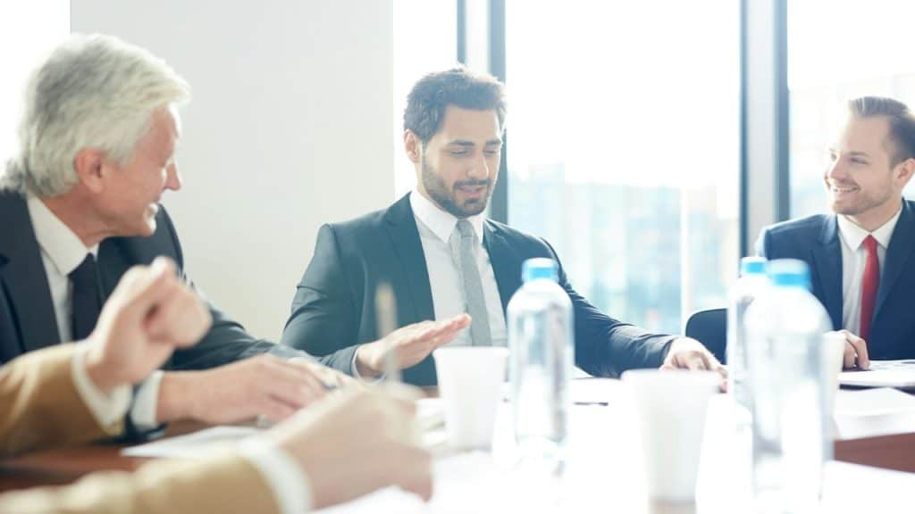 Three male business colleagues are sitting around a conference table in an office.