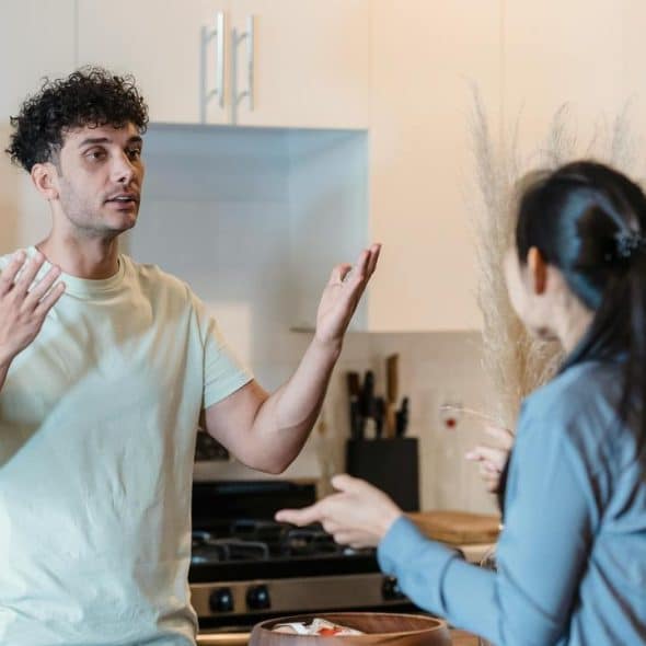 A man and woman having a serious conversation in a kitchen.