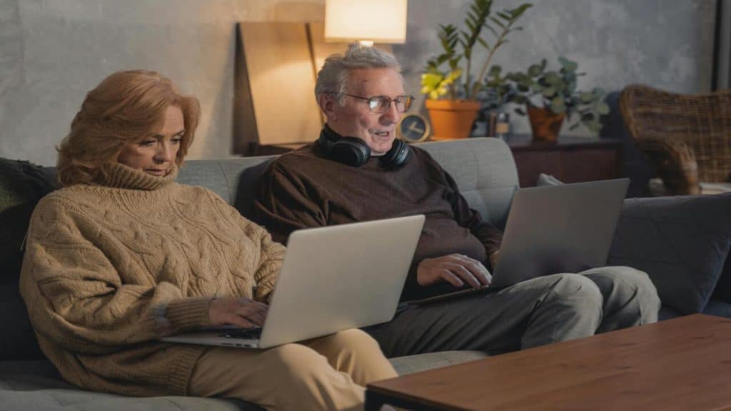 An elderly couple using their laptops and ignoring each other
