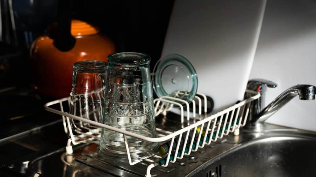 A dish rack with clean glasses drying by the sink.