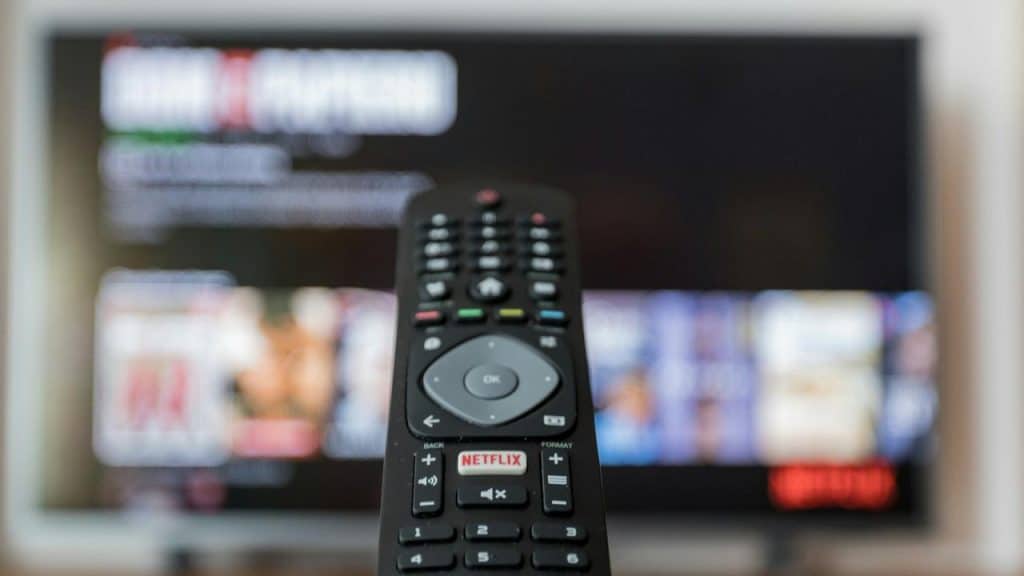 A TV remote control pointed at a television screen with Netflix on display.
