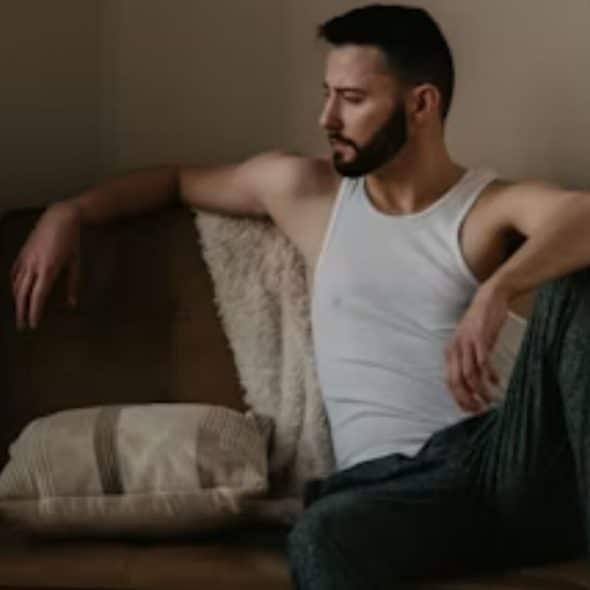 A man sitting on a couch, looking lost in thought