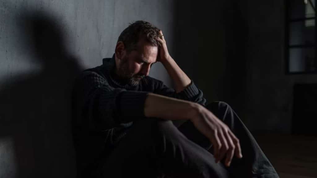 Man sitting on the floor at night unable to sleep