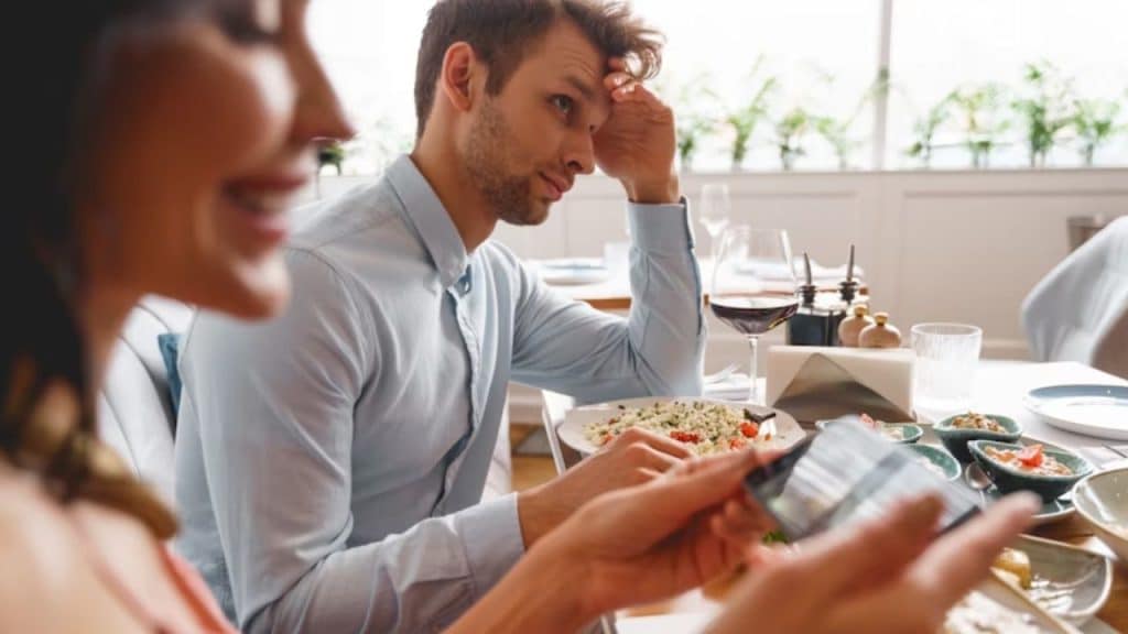 Man sets up dinner while partner scrolls on phone