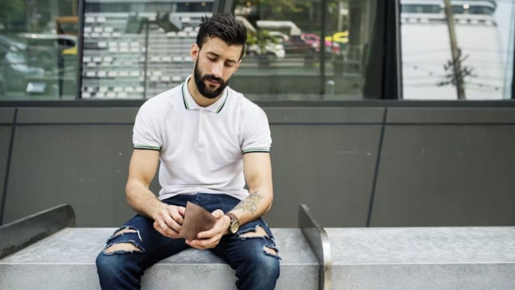 A man staring at bills in his wallet, looking overwhelmed