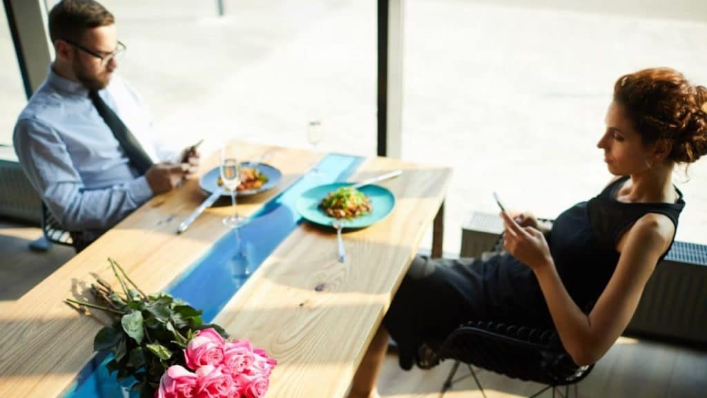 Man ignoring topics about future plans by focusing on his phone and keeping himself busy