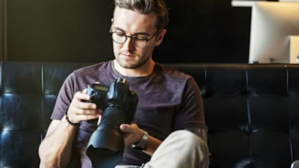 Man sitting on couch alone checking pictures on his camera