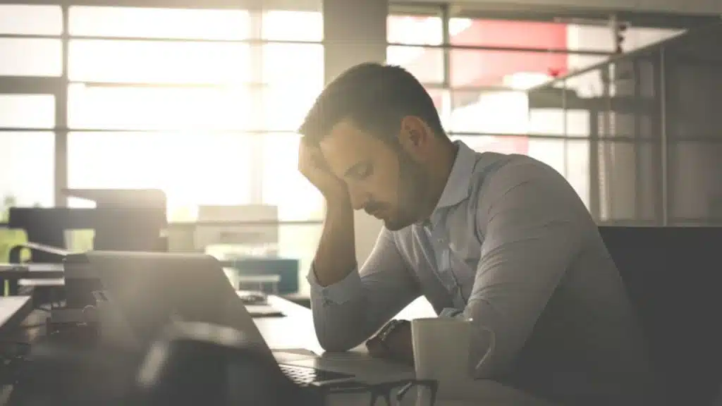 Man sitting at kitchen table with head in hand