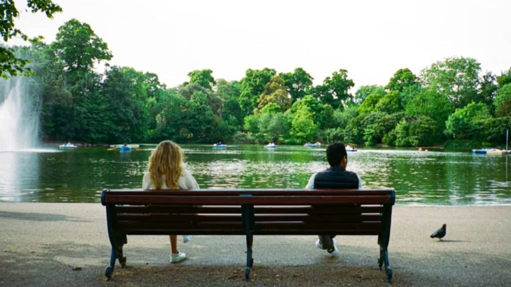 Couple sitting  away from each other in silence on a bench, both looking away