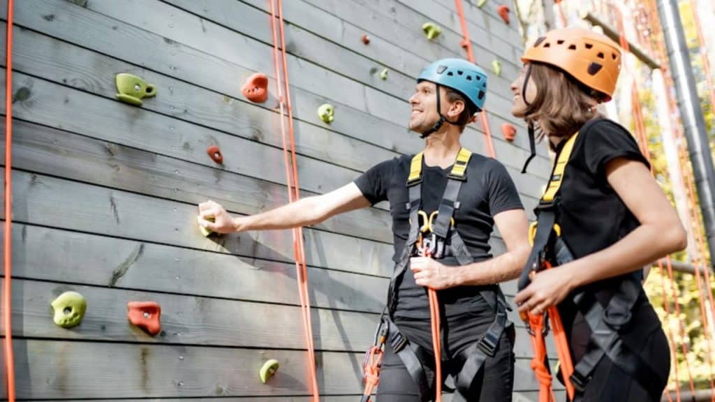 Couple climbing a rock wall together at an outdoor gym