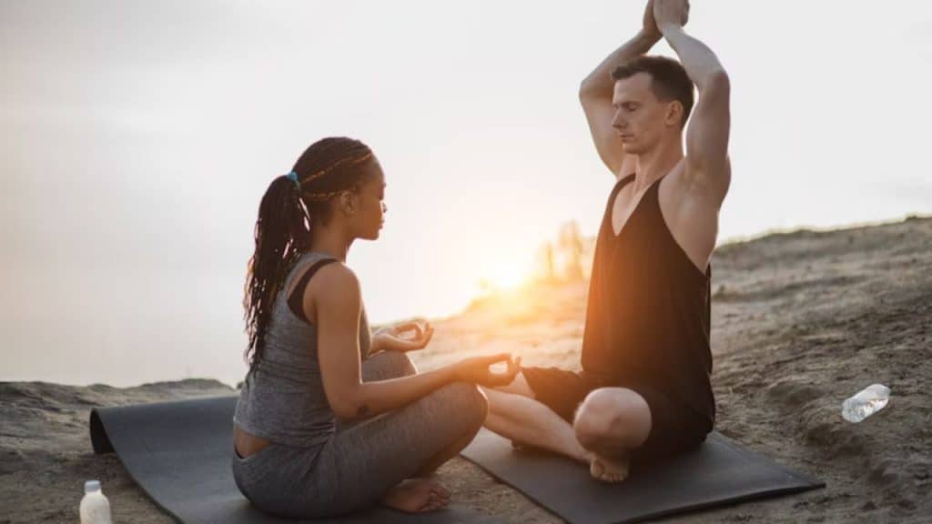Couple meditating with closed eyes on yoga mat during sunrise