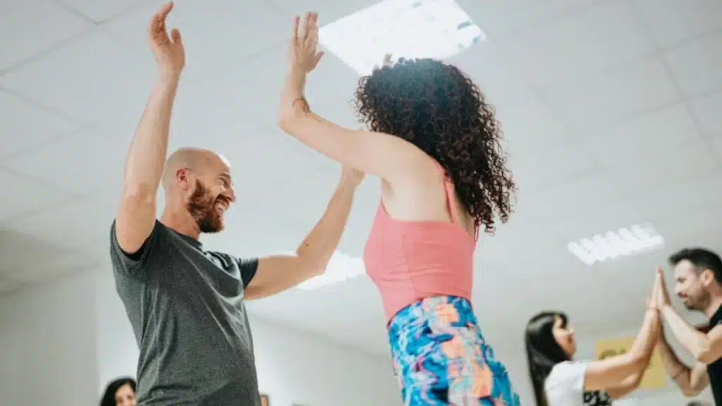 Couple smiling while learning salsa dance moves in a studio