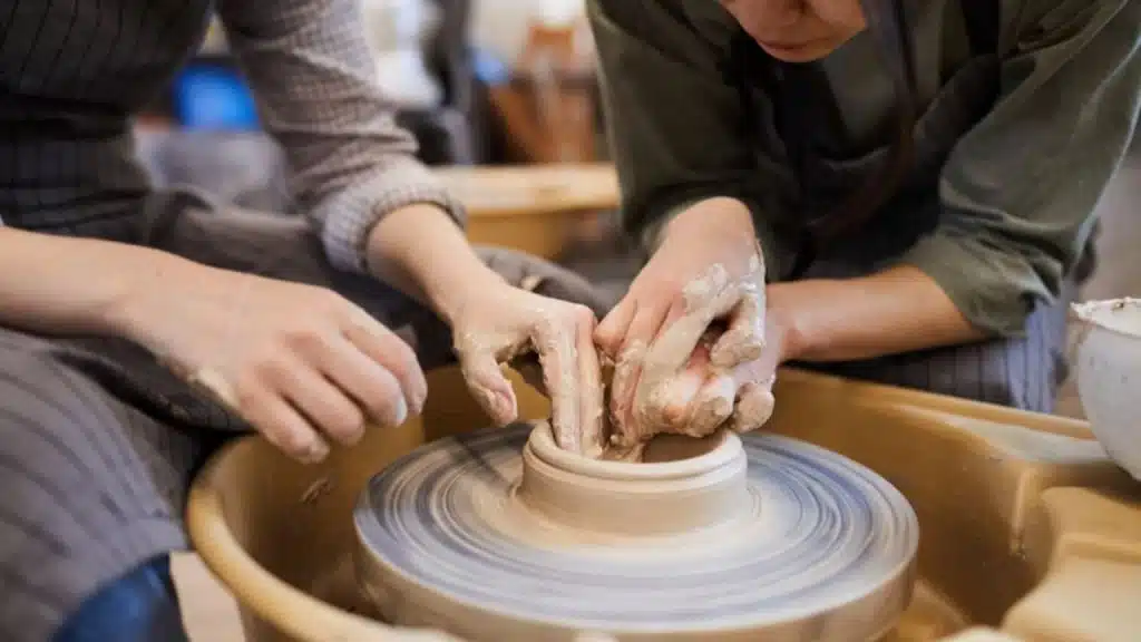 Couple learning pottery together, shaping clay on a wheel