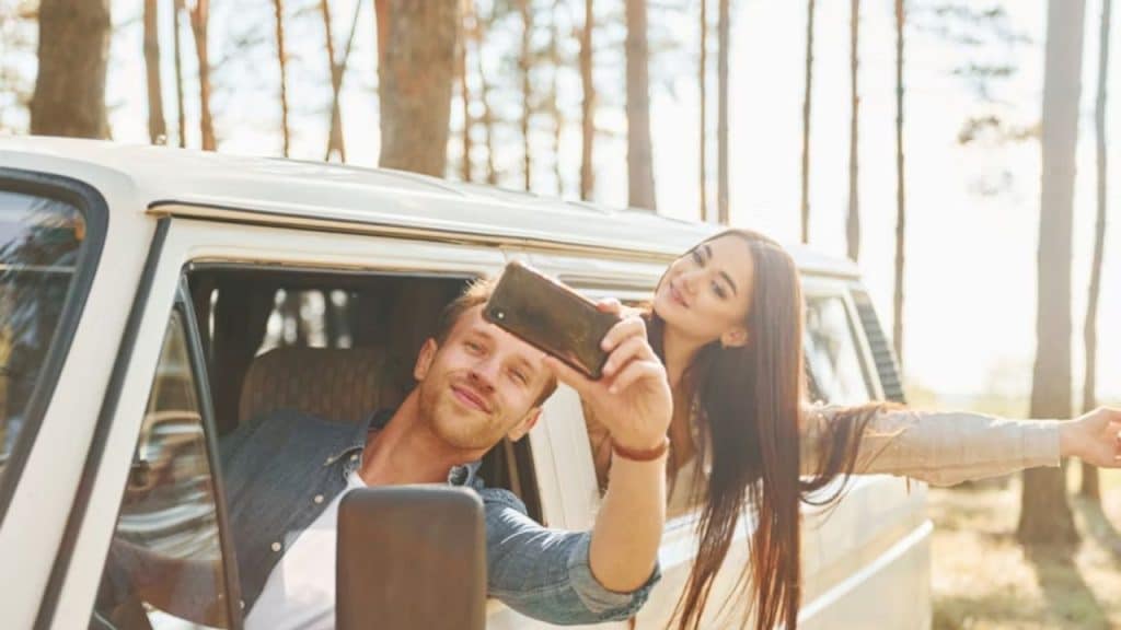 Couple taking selfie on a road trip in a convertible