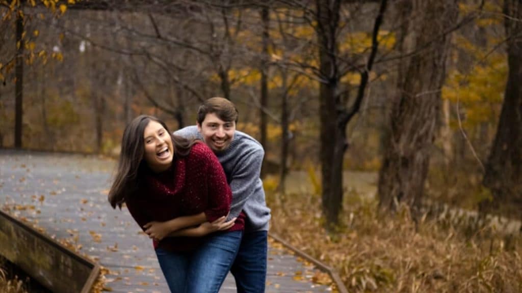 Couple laughing while playfully chasing each other in a park