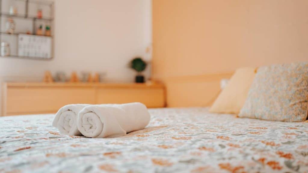 A pair of rolled up towels sitting on top of a bed.